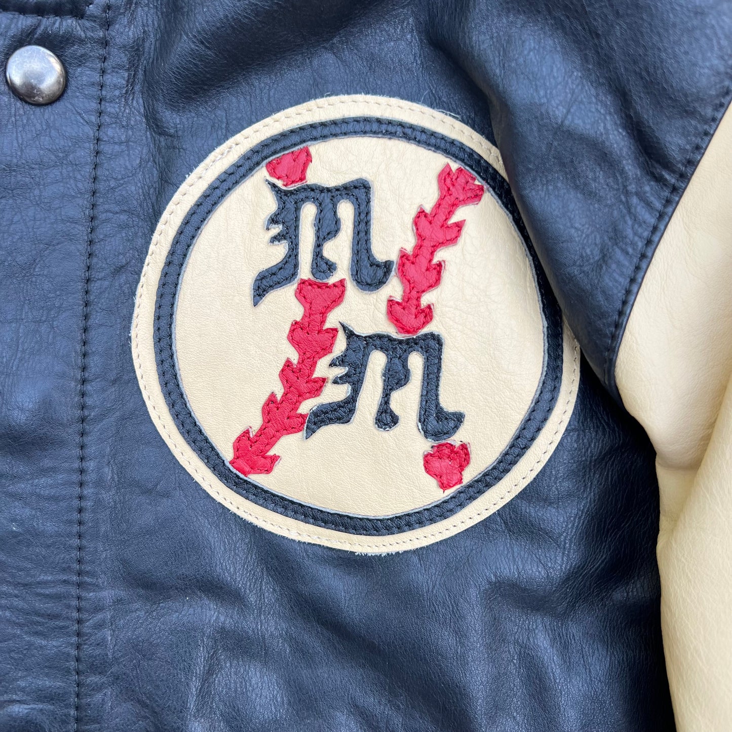Left side on the front of jacket a small patch of a baseball