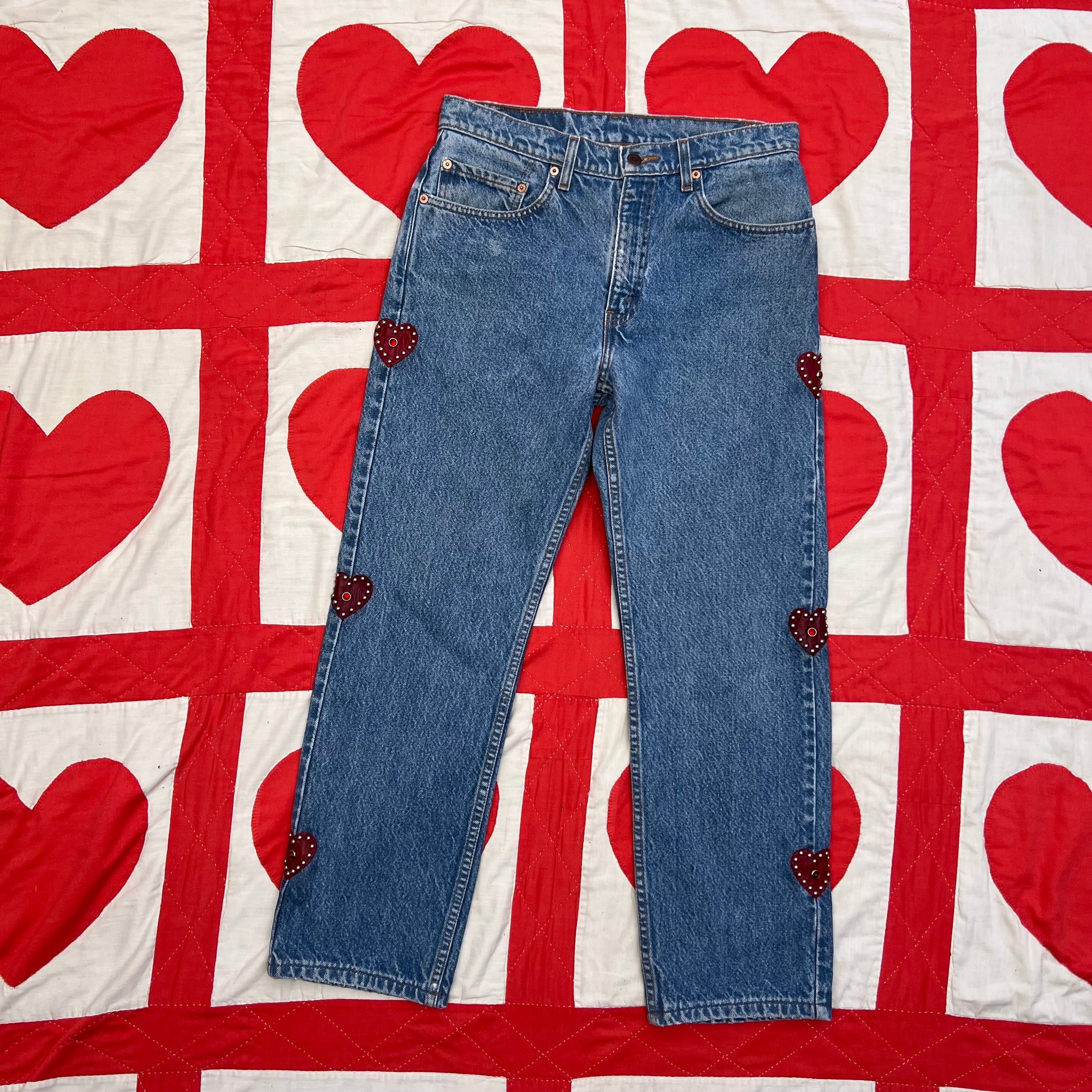 Custom vintage Levi’s with cut out red leather hearts on each side of the legs.