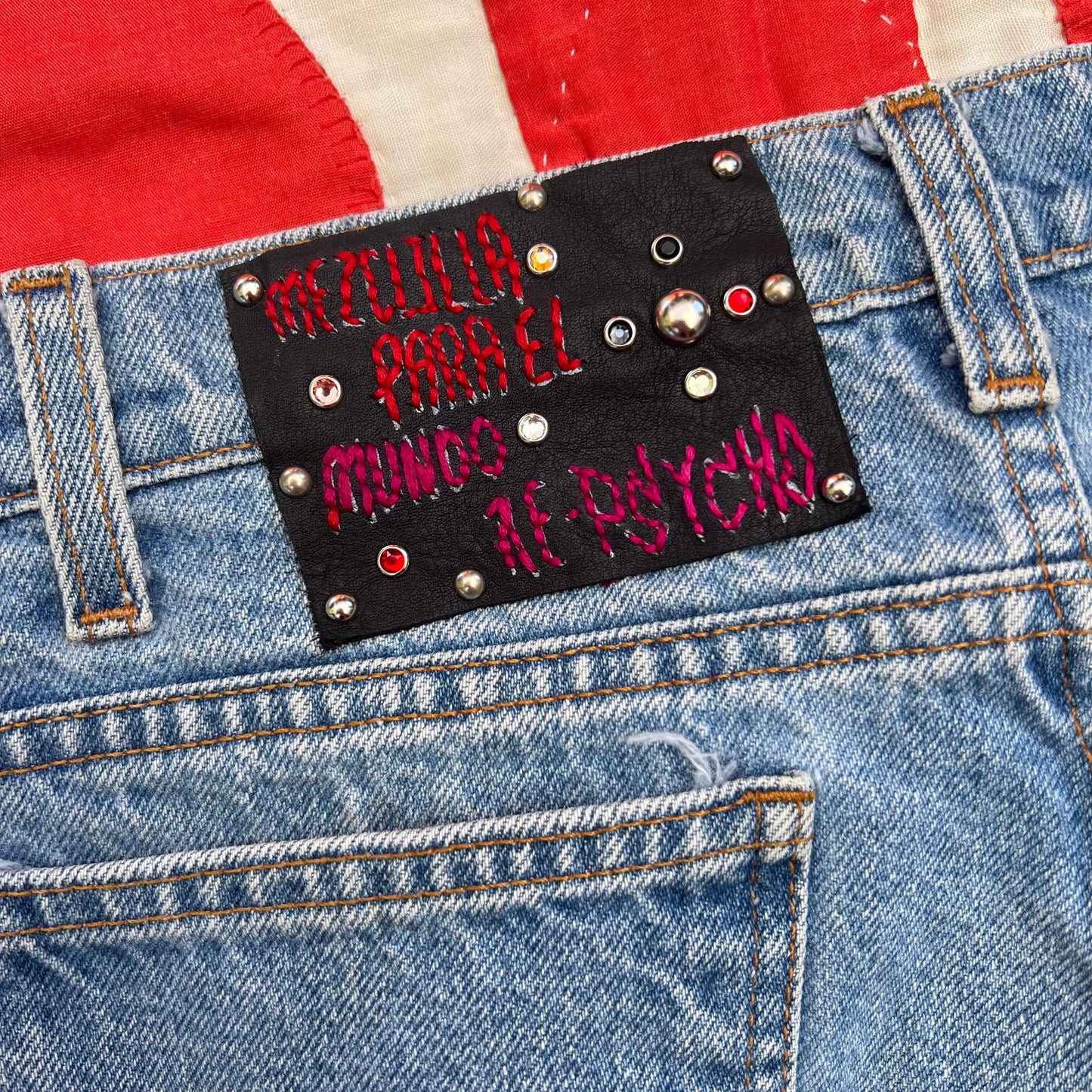 Third photo; shows a custom leather tag with red and pink stitching & stud work.